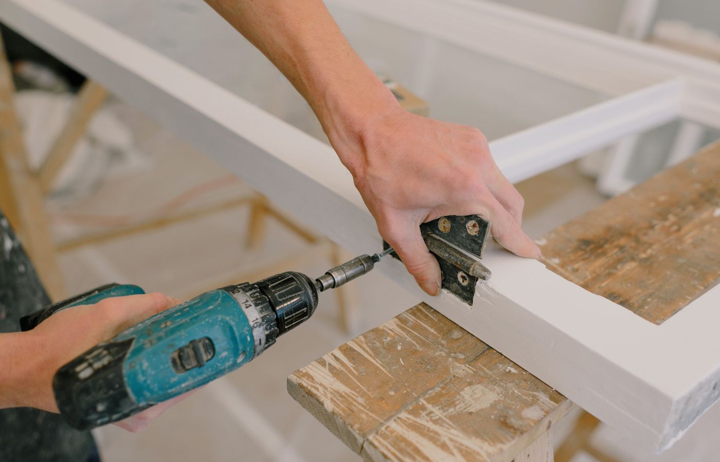 A metal hinge being fitted to a wooden frame.