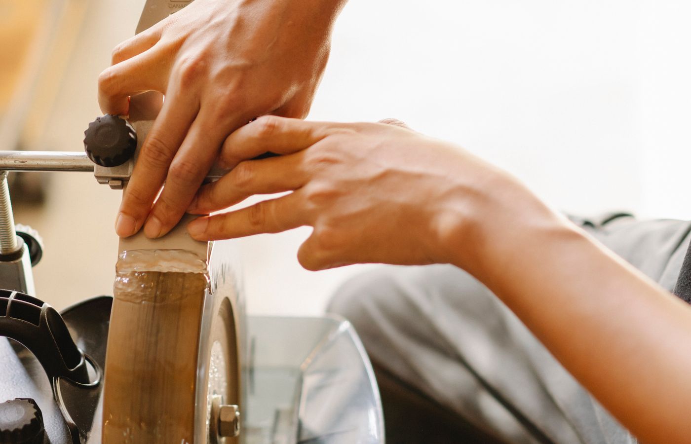 A workshop grinding wheel being used to sharpen a metal tool.